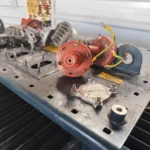 Un transformador de distribución dañado en el taller de reparación, con los aisladores y otros componentes dispersos sobre la tapa tras intento de robo.