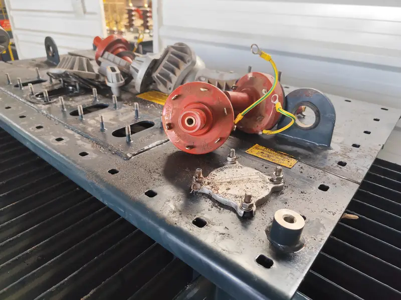Un transformador de distribución dañado en el taller de reparación, con los aisladores y otros componentes dispersos sobre la tapa tras intento de robo.