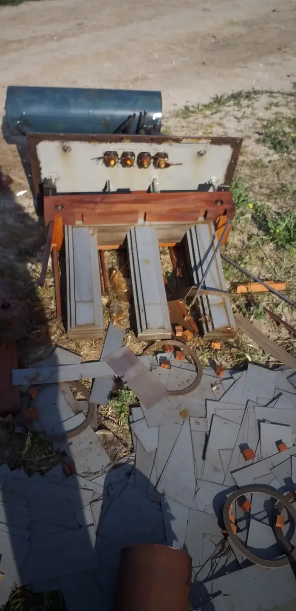 Transformador eléctrico desmantelado en campo, mostrando el circuito magnético, sin el bobinado de cobre y el aceite contaminante vertido en la tierra.
