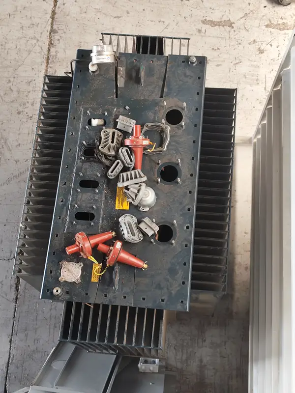 Vista superior de un transformador eléctrico dañado por vandalismo, con sus componentes rotos y dislocados.